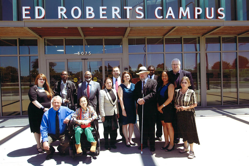 12 people taking a photo in front of the Ed Roberts Campus building